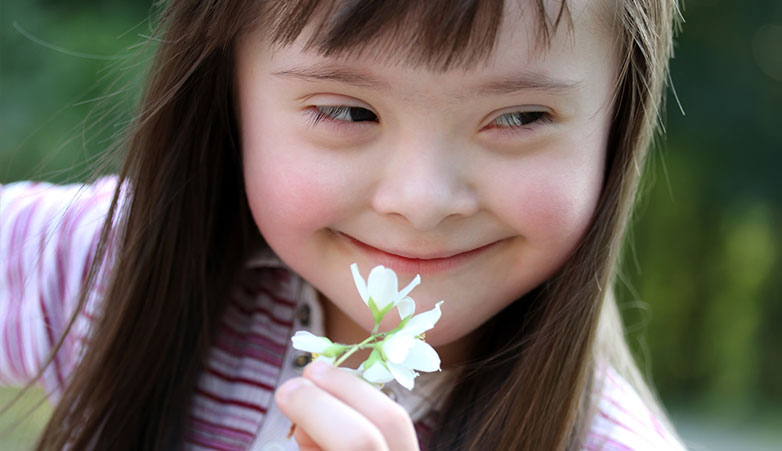 Young Girl holding a flower smiling | Simcoe Community Services