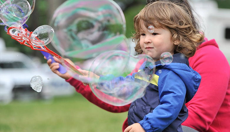 Young child playing with bubbles outside | Simcoe Community Services