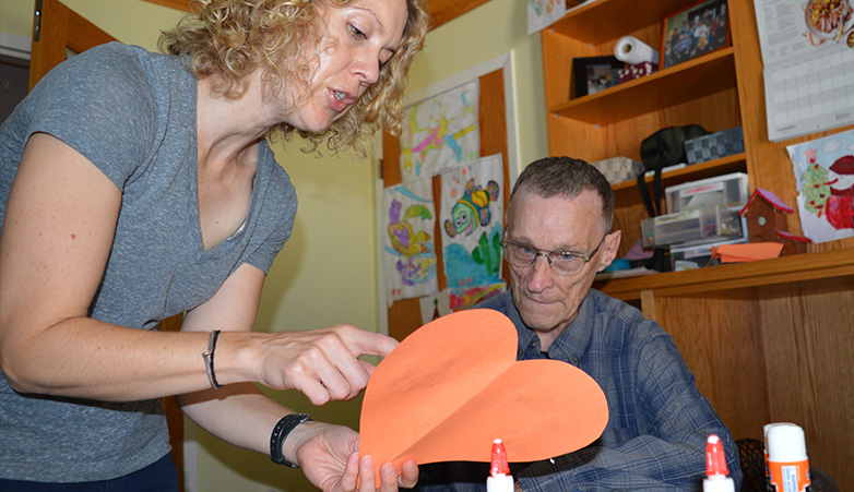 Woman helping an elderly man do arts and crafts | Get Involved | Simcoe Community Services